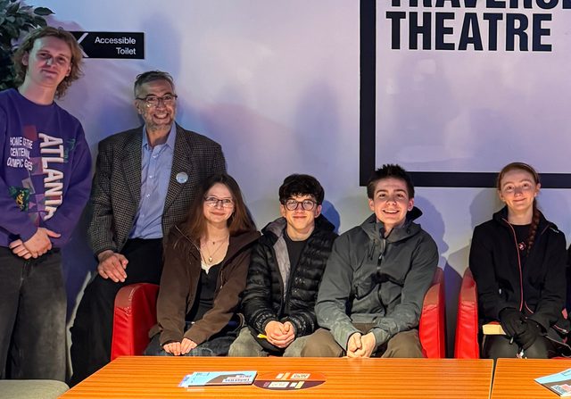 Young writers from the Citizens Collective seated posing for photo with author Ryan van Winkle.