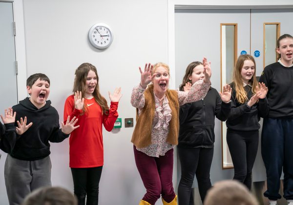 Row of school pupils with hands in the air laughing or shouting
