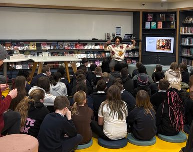 Photo from behind a class of school kids sitting during a talk by author Joseph Coelho