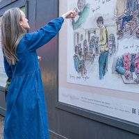 Person in blue pointing at large poster with illustrations