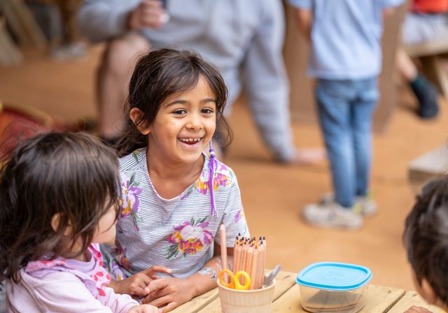 Children smiling while doing a craft in the Kids Zone