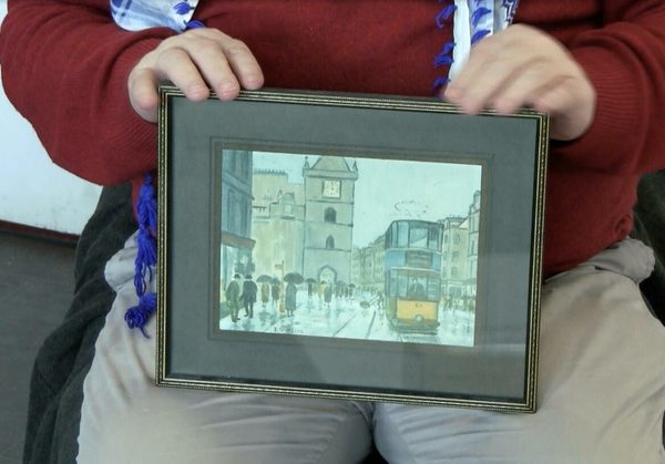 Person holding up a framed drawing of a street