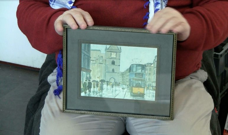 Person holding up a framed drawing of a street