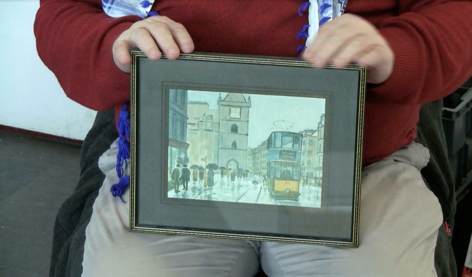 Person holding up a framed drawing of a street