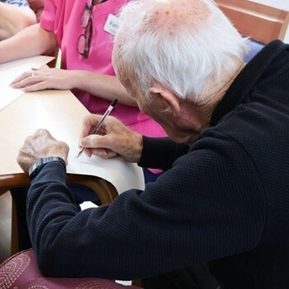 Photo of a white haired man writing