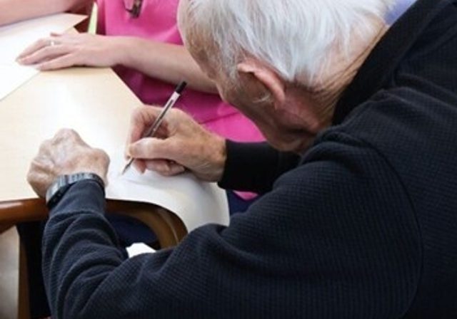 Photo of a white haired man writing