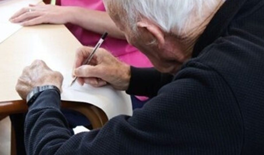 Photo of a white haired man writing