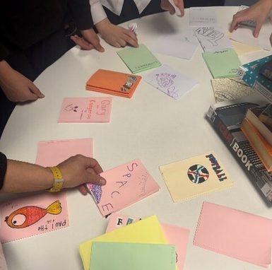 A collection of zines on a table with hands working on them