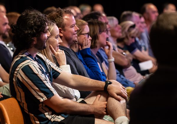 Audience seated in a row looking right across the photo