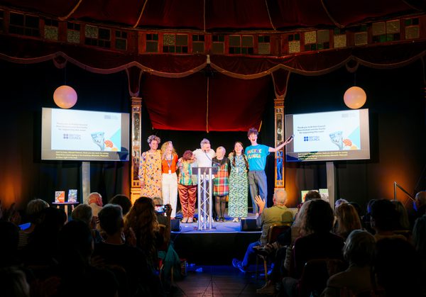 Group of international authors standing in a line on stage in front of audience
