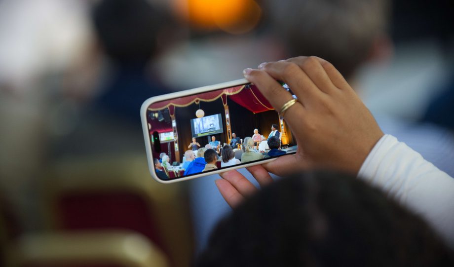Person holding up phone taking photo of event in Spiegeltent
