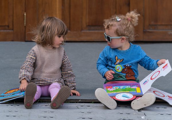 Two small kids sitting with books open in their laps