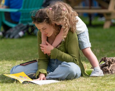 Adult and child reading sitting on grass