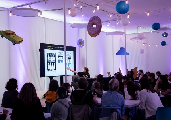 Photo of audience in event in Venue C with screen and decoration hanging from ceiling